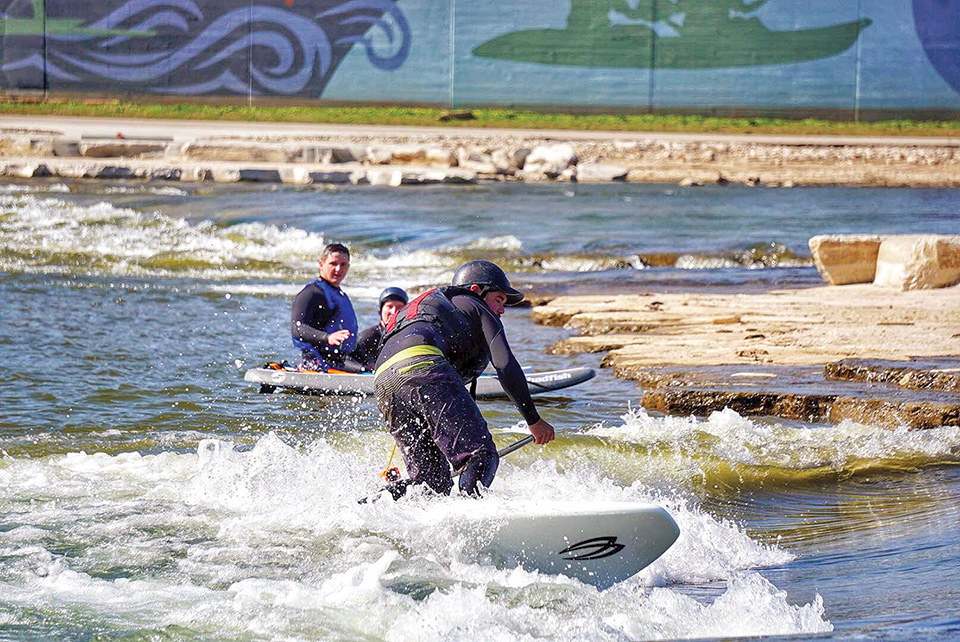 People surfing and paddleboarding on the Great Miami River in downtown Dayton (photo courtesy of Great Miami Riverway)