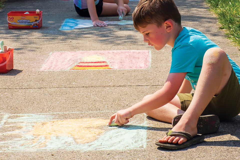 Boy drawing on sidewalk with chalk (photo courtesy of Main Street Vermilion)