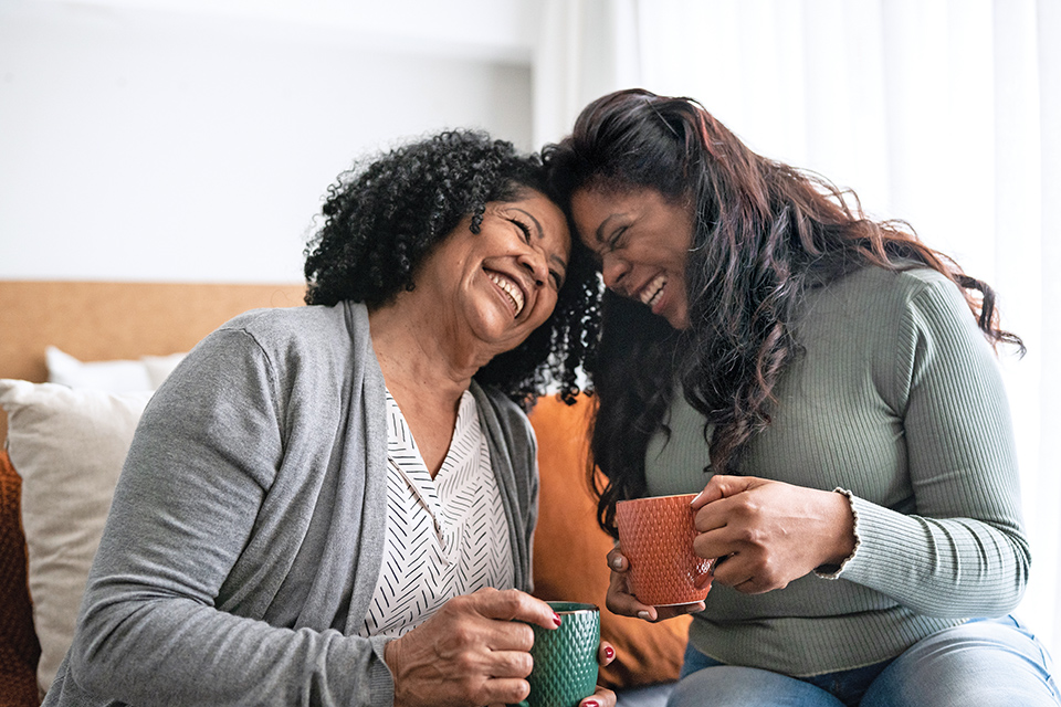 Women laughing and having coffee (photo by iStock)