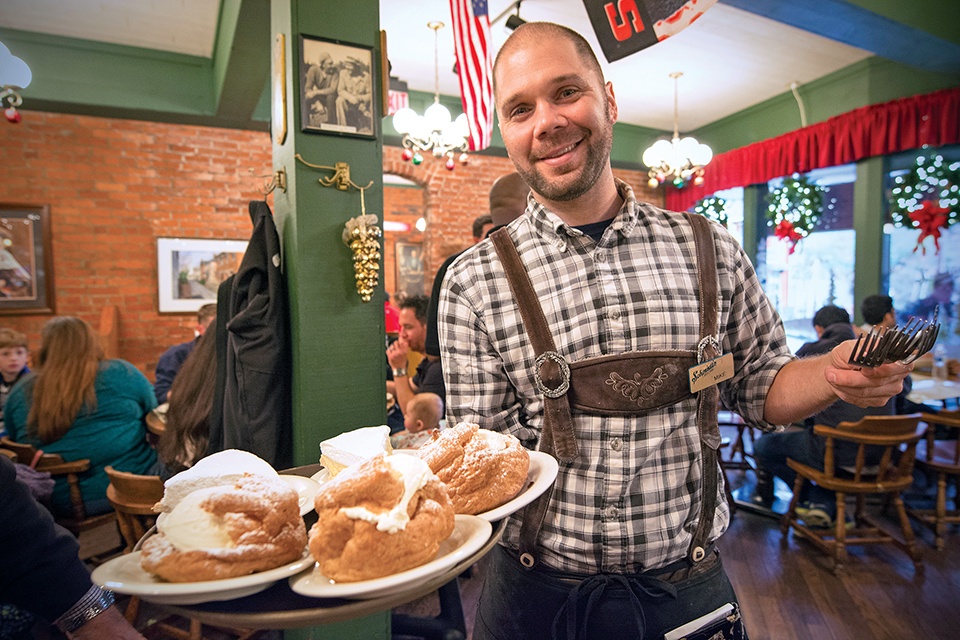 Server holding cream puffs at Columbus’ Schmidt’s Sausage Haus (photo courtesy of Experience Columbus)