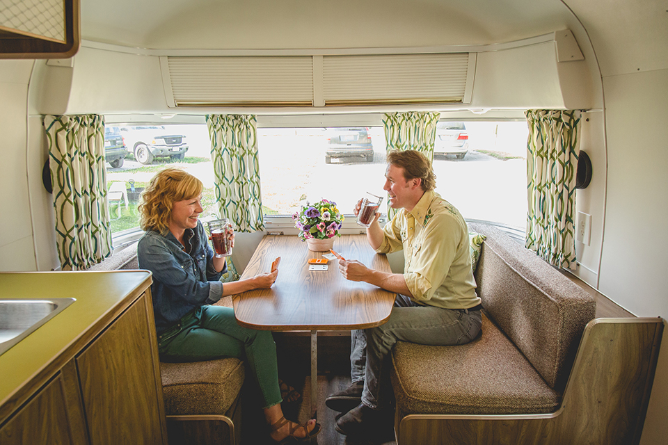 Man and woman playing cards at a table inside one of the Argosy trailers in Coshocton (photo courtesy of Camille McPeek)