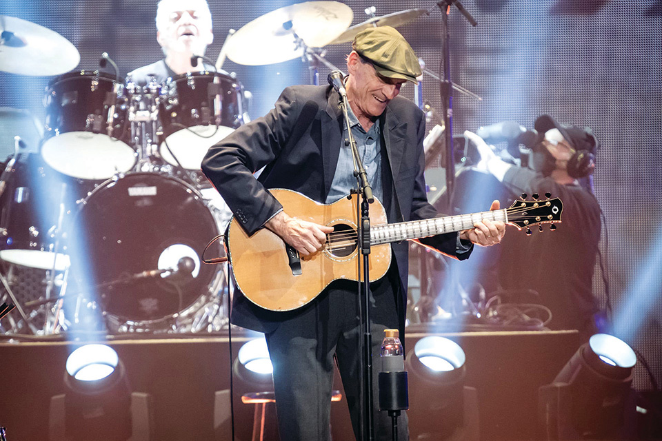 James Taylor playing guitar on stage (photo by Elliot Deseure)