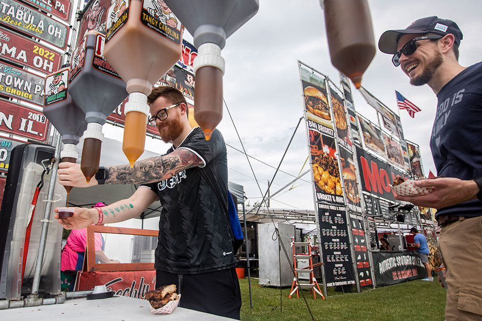 Man at sauce dispenser at Northwest Ohio Rib Off in Toledo (photo courtesy of The Blade, by Rebecca Benson)
