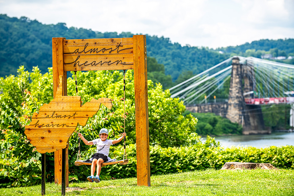 Child by Almost Heaven, West Virginia sign in Wheeling (photo courtesy of Wheeling Convention & Visitors Bureau)