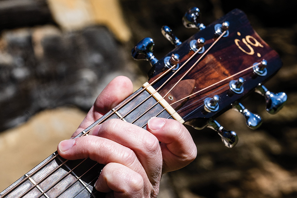 Close-up of musician Josh Compton playing guitar (photo by Ken Blaze)