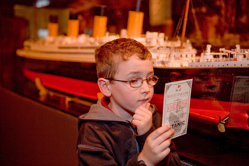 Boy looking at boarding pass at “Titanic” at COSI in Columbus (photo courtesy of COSI)